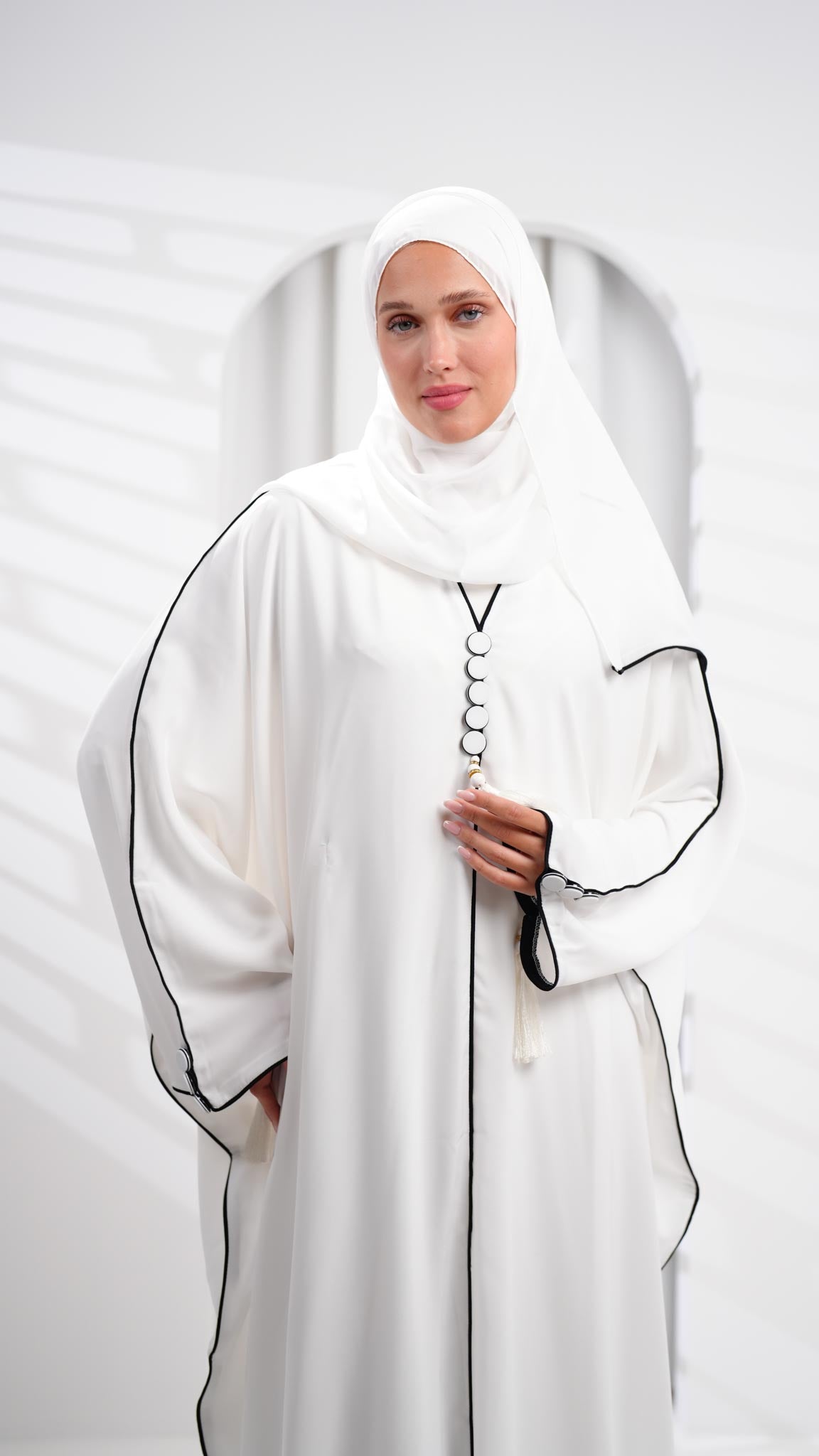 عباية خليجية بيضاء مزينة بشرابات على شكل فراشة