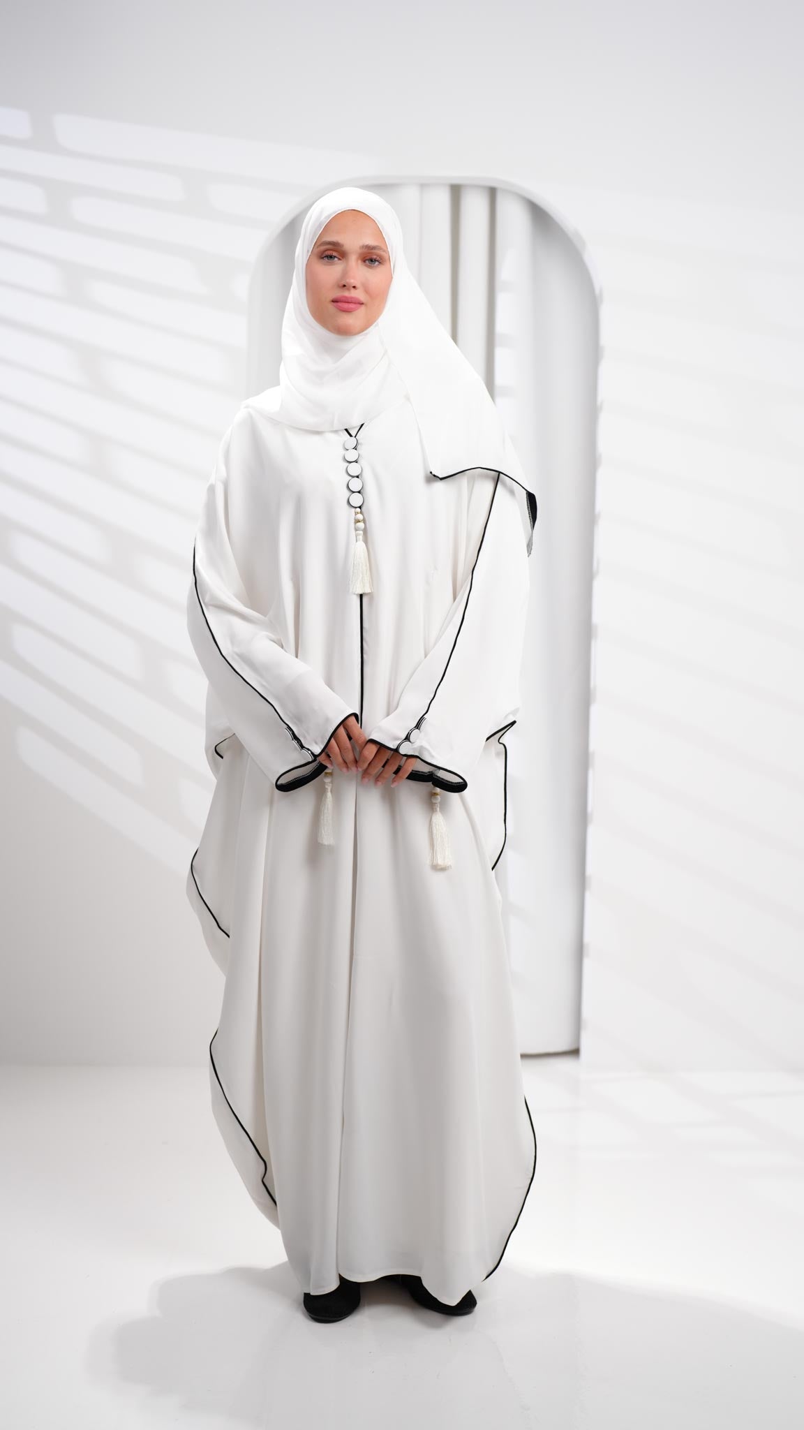 عباية خليجية بيضاء مزينة بشرابات على شكل فراشة